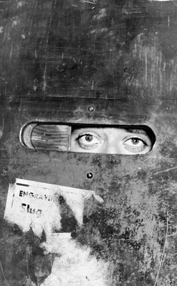 Staring eyes regard you through the peephole of a steel door.